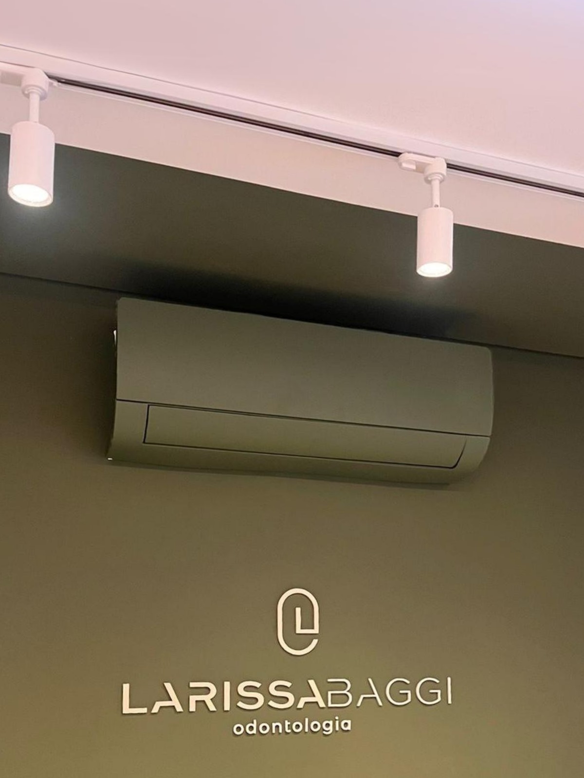 Split hi-wall pintado em verde-oliva na parede de uma clínica odontológica