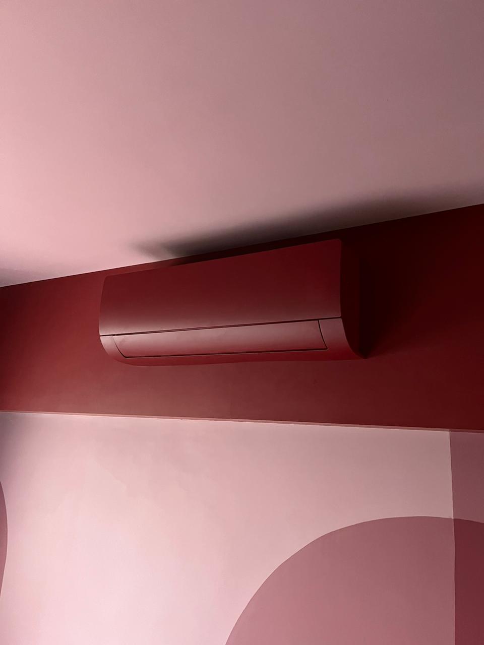 Split hi-wall pintado em rosa integrado à parede de um quarto